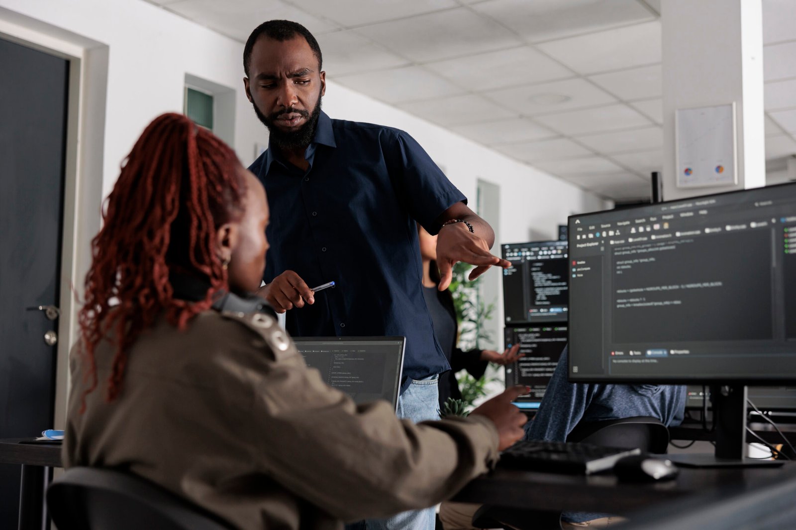 African american engineers typing machine learning html code on computer, sitting at desk table in big data office. Software developers working on database system with html script in it security agency.